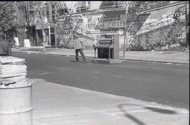 Man pulling piano down street, St. Marks Place just west of 2nd Avenue. 1980.<br/>